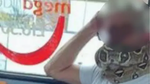 PA Media Man using snake as face mask