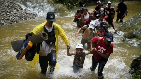 A group of migrants from Venezuela, Ecuador and Haiti cross the Rio Muerto river in the Darien Gap, as they continue their journey to the U.S. border, in Acandi, Colombia July 9, 2023.