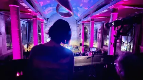 Colin Moody A woman and man seen from behind as they watch a live performance in Bristol