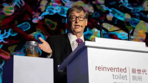 AFP Bill Gates motions toward a jar of human faeces on stage