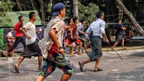 Getty Images People clash with security forces as they continue to protest against military coup and detention of elected government members in in Hlaing Thar Yar Township, Yangon, Myanmar on March 14, 2021