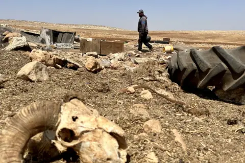 BBC Ammar Abu Alia walks through the burnt remains of his home in al-Qabun