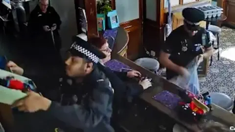 SWNS Officers putting golliwog dolls in a bag behind the bar