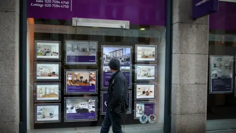 Getty Images A man walks past an estate agency in West London