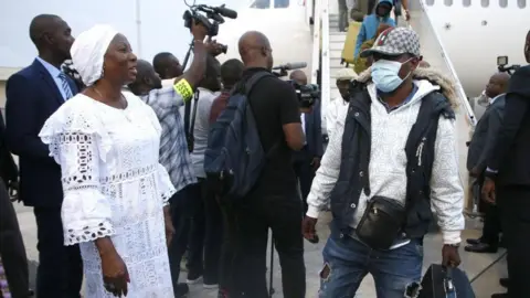 EPA Ivorian Minister of State and Minister of Foreign Affairs Kandia Camara (L) welcomes some of the hundreds of sub-Saharan Africans arriving from Tunisia at the airport in Abidjan, Côte d'Ivoire, on 04 March