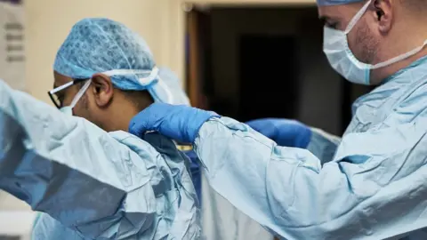 Getty Images Medics putting on personal protective equipment