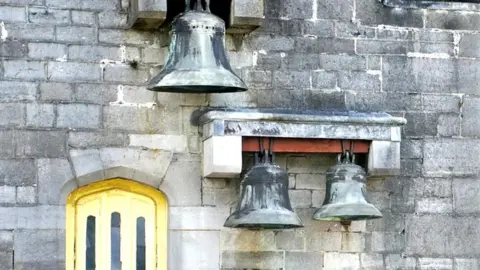 Cliff Day three bells on the outside of a stone wall