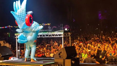 Hello Content for Camp Bestival Shropshire Fat Boy Slim in a parrot costume in front of the crowd