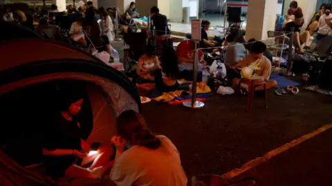 REUTERS Sera, 14, and Eliza, 14, prepare to sleep in their tent as they queue overnight for Taylor Swift concert tickets outside a post office in Singapore, Singapore July 6, 2023