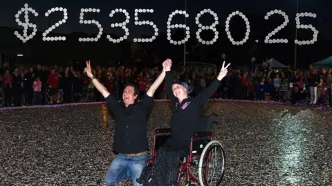 Facebook/@loveyoursister Image shows Connie and Sam Johnson underneath a sign showing $2,535,680.25