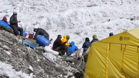 BBC/Anbarasan Sherpas and belongings outside their tents at base camp