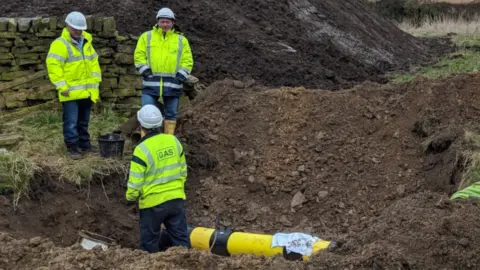Tom Hughes Three engineers repairing damage to a gas pipe