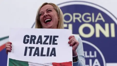 Leader of Brothers of Italy Giorgia Meloni holds a sign at the party's election night headquarters