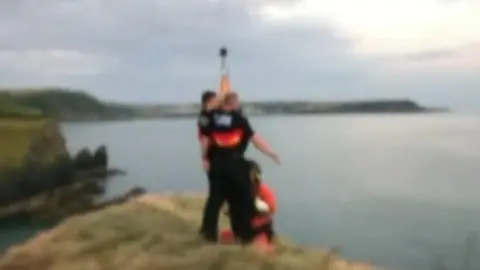 RNLI Police officers being winched to safety by helicopter