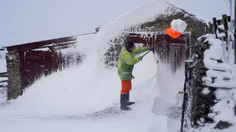 Owen Humphreys/PA Ken Emerson clearing a snow drift in Lanehead, County Durham.