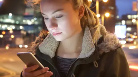 Getty Images A stock photo of a young woman looking at a phone