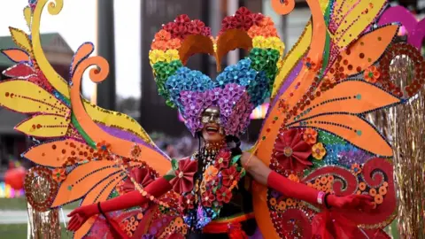 EPA A participant is seen in a huge elaborate rainbow-themed butterfly costume