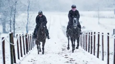 PA Media Horses on the gallops in the snow at Sam Drinkwater's Granary Stables in Upper Strensham, Worcestershire.