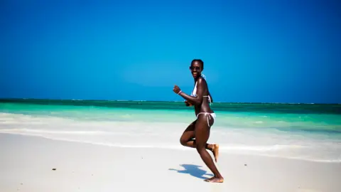 Getty Images A woman running on a beach in Diani , Kenya - generic shot