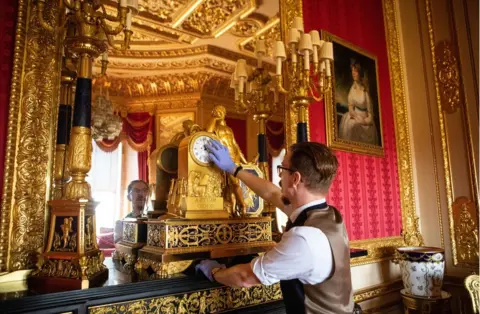 Antonio Olmos Fjodor changes the time on a clock in the Crimson Drawing Room