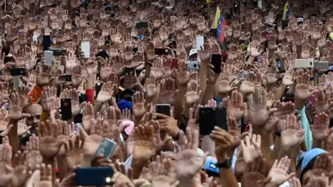 AFP Venezuelans cheer Mr Guaidó as he declares himself interim president on 23 January