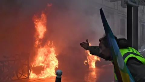 AFP Yellow vest protester gesturing at a burning car