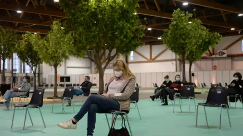 Reuters A person waits after receiving a vaccine dose in Brussels