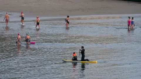 PA/Owen Humphries Swimmers close to the shore in Cullercoats on 30 March