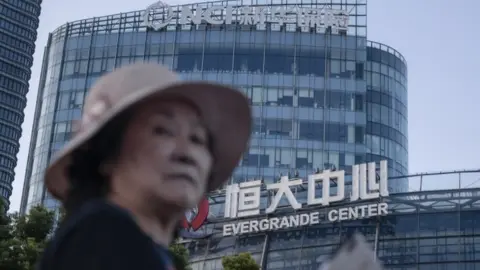 EPA A woman walks past the Evergrande Center in Shanghai, China, 21 September 2021.