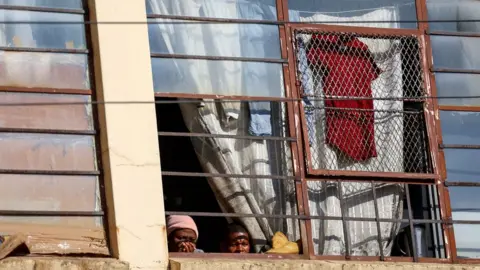 Reuters Residents watch from a window the scene of a deadly blaze, in Johannesburg