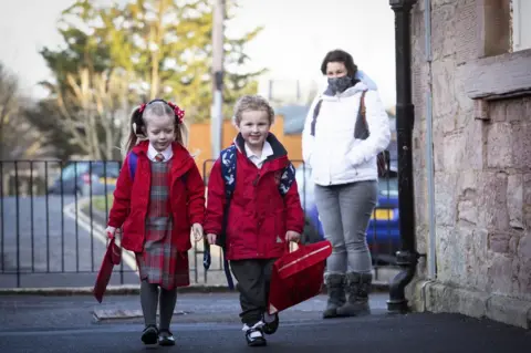 PA Media P1 pupils Grace Lee (left) and classmate Grace McKeeman, both aged 5, arrive for their first day back at Inverkip Primary School