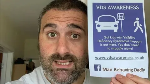 Simon Harris Man with beard holding a sign