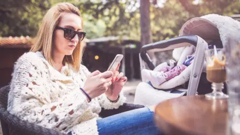 Getty Images Mum with baby on her phone