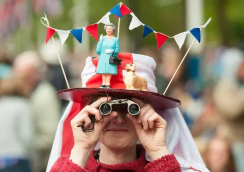 WPA Pool/Getty Images A woman in a fancy dress hat featuring Queen Elizabeth II and a corgi, pictured during the Diamond Jubilee concert at Buckingham Palace in 2012