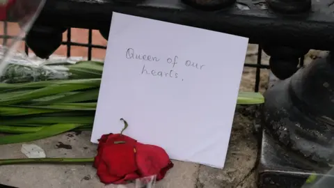 Card with 'Queen of our hearts' written with rose