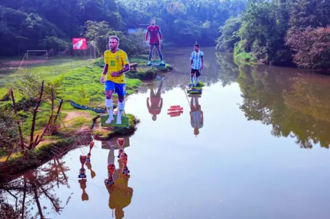 Arun chandra bose Fans wave flags next to the giant cutouts of players from Brazil's Neymar (L), Portuguese Cristiano Ronaldo (C) and Argentine Lionel Messi, erected by football fans in river Cherupuzha at Kozhikode in India's Kerala state on November 7, 2022, ahead of the Qatar 2022 FIFA World Cup football tournament.