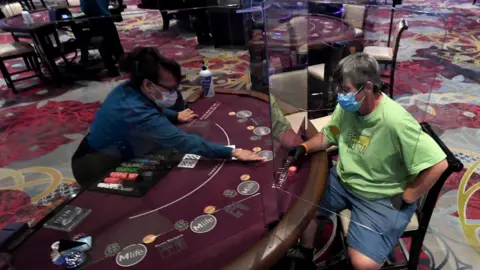 Getty Images Nila Davis (L) deals cards to Becky Lewis of Texas at a blackjack table with plexiglass safety shield dividers at Excalibur Hotel ^ Casino after the Las Vegas Strip property opened for the first time since being closed in mid-March because of the coronavirus