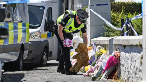 Getty Images Police officer with floral tributes
