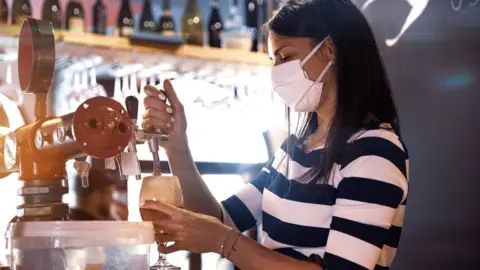 Getty Images Woman pouring pint in pub