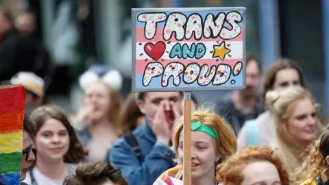 Getty Images A participant holds a sign saying "Trans and Proud" during the Glasgow Pride march