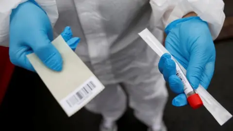 Reuters Hands holding out a Covid-19 test kit