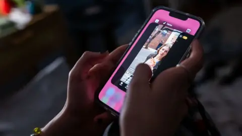 Getty Images Photo illustration of a teenager using TikTok on her mobile phone
