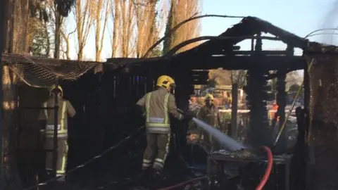 Staffordshire Fire and Rescue Firefighters hose down burnt enclosure