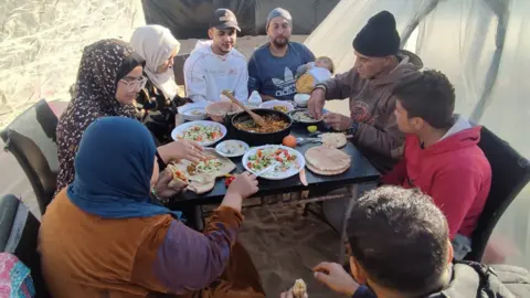 Fourni à Amal et à sa famille mangeant près de leur tente à Al Mawasi