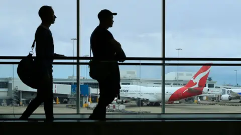 Getty Images Two men walk through Sydney Airport