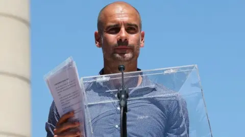 Reuters Manchester City's manager Pep Guardiola holds a ballot box during a pro-independence rally in Barcelona (11 June 2017)