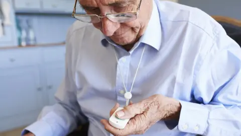 Getty Images An elderly man uses his pendant alarm