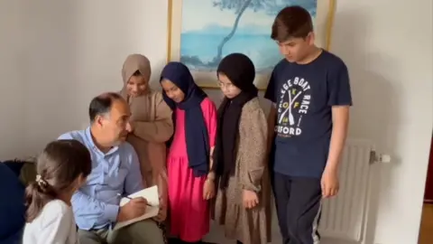 Abdul Wali Shelgari with his six children in a hotel in Sussex.