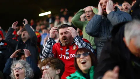 Reuters Wrexham fans hold their heads in their hands