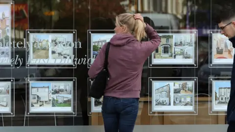 Getty Images A woman looking at homes to buy at an estate agent's